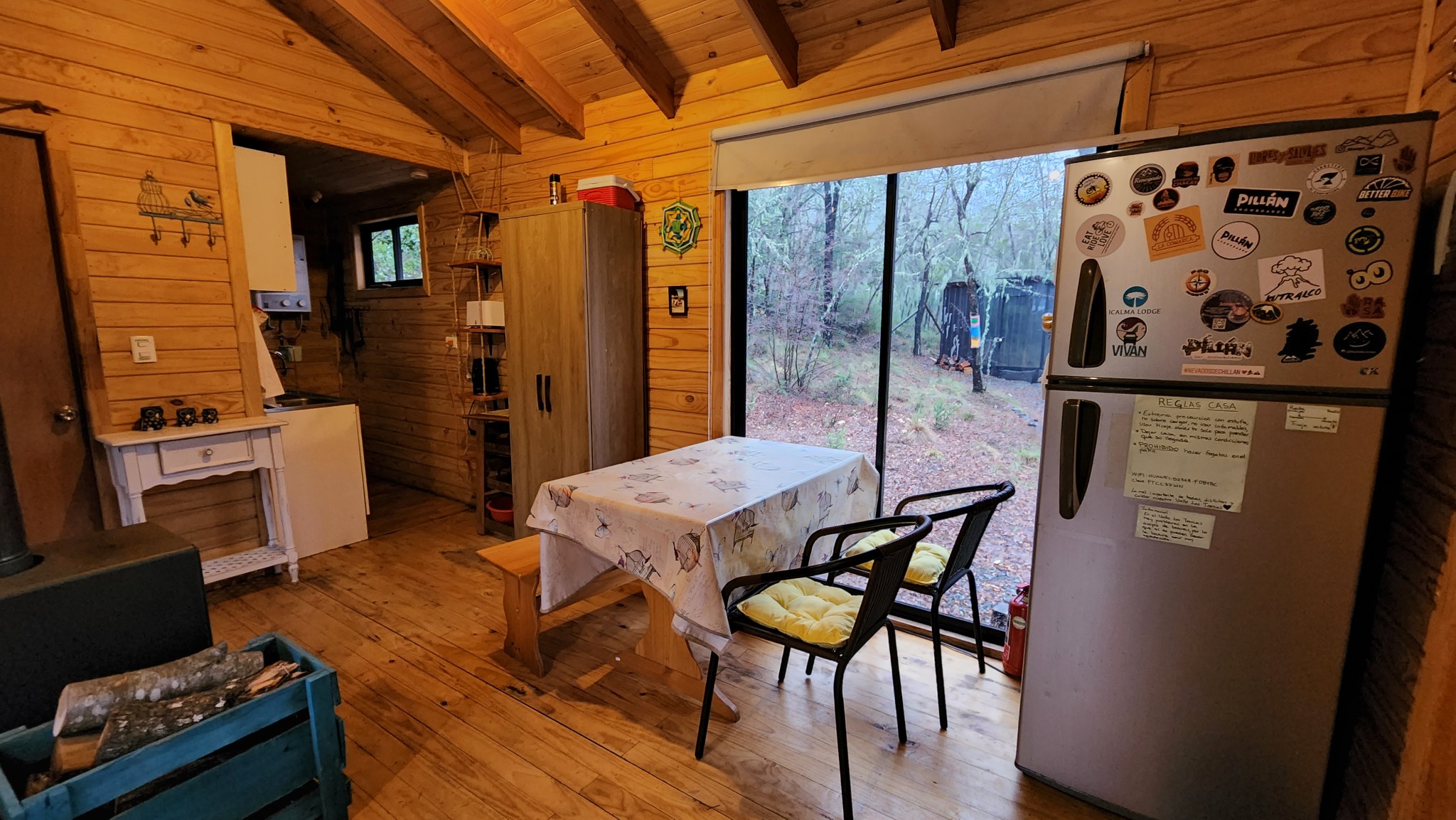 Comedor de la cabaña junto a la cocina y una gran ventana al bosque